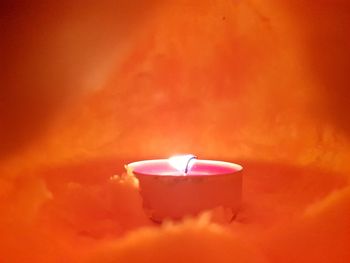 Close-up of lit tea light candle on red flower