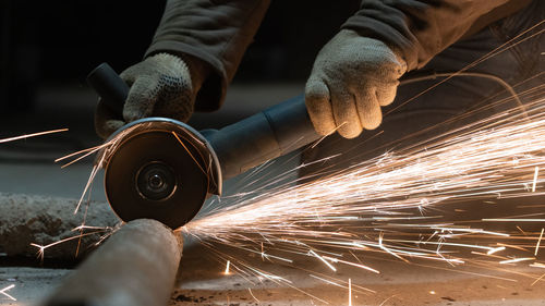 Cropped hands of man cutting metal in workshop