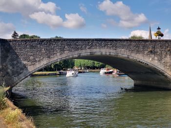 Arch bridge over river against sky