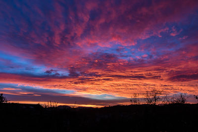 Low angle view of dramatic sky over silhouette landscape