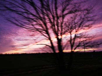 Silhouette trees on field against romantic sky at sunset