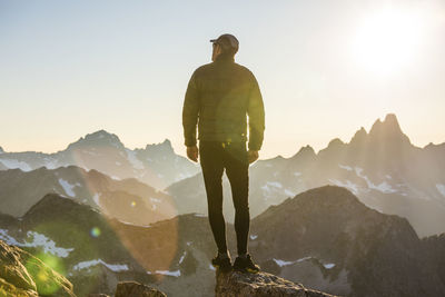 Lone hiker on mountain summit at sunset with view.