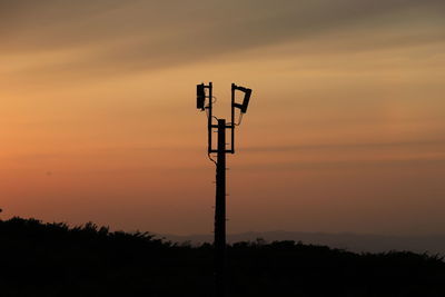 Low angle view of silhouette communications tower against romantic sky at sunset