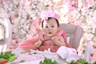 Portrait of cute baby girl sitting on pink flower