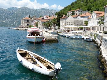 Sailboats moored on sea by buildings in city