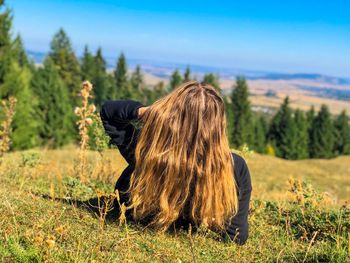 Rear view of woman sitting on field