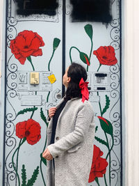 Rear view of woman standing by red wall with text