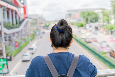 Rear view of woman sitting on railing