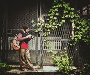 Full length of woman wearing hijab while looking at camera against fence