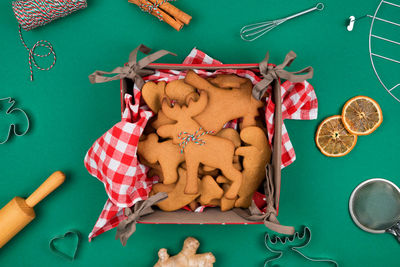 Top view of freshly backed christmas gingerbread cookies on red plaid napkin, fresh ginger, cinnamon