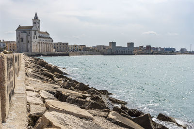 Buildings by sea against sky in city