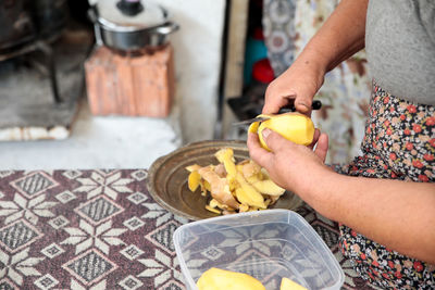 Midsection of woman peeling potato