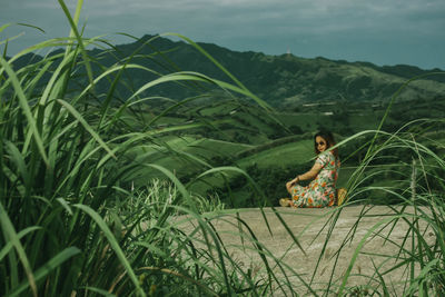 Woman sitting on grass in field