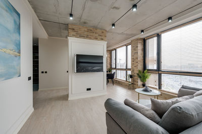 Interior in a modern style and a view of the tv and part of the kitchen near the large windows 