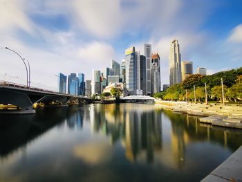 Bridge over river by buildings against sky in city
