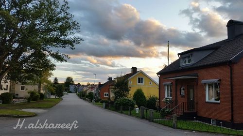 Road by houses in town against sky