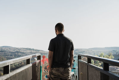 Rear view of man standing on footbridge