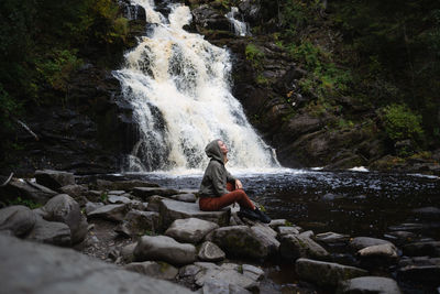 Rear view of woman sitting on rock