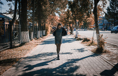 Rear view of woman walking on footpath during autumn