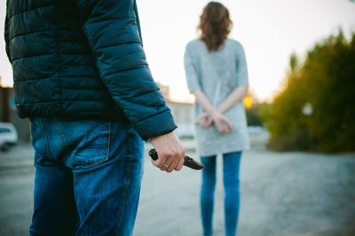 Rear view of man standing with knife against woman