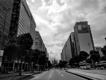 Road by buildings against sky in city