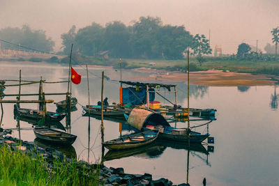 Sailboats moored in lake against sky