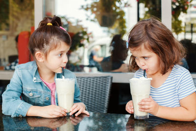 Siblings having milk shake at table in restaurant