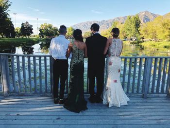 Rear view of friends standing against railing