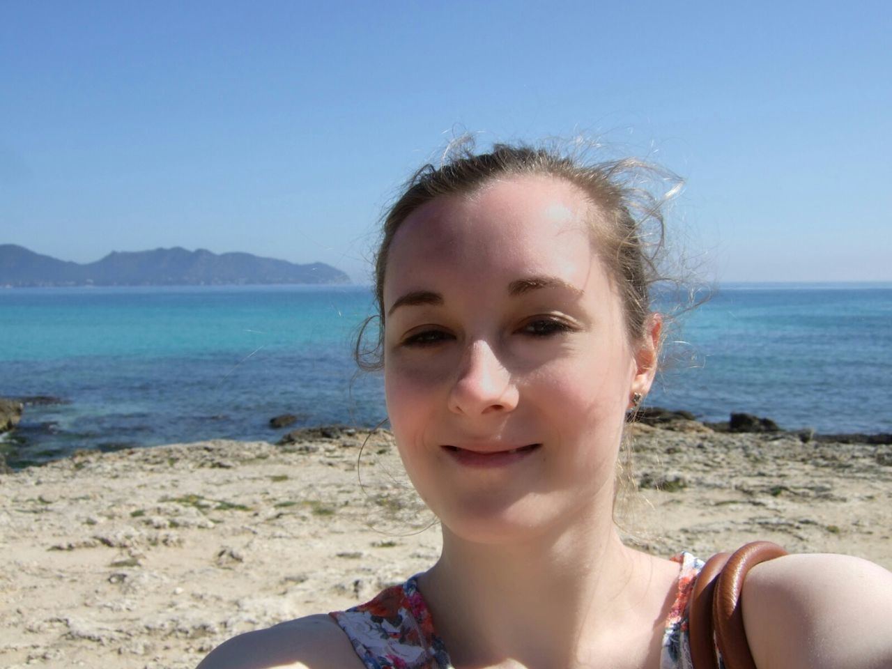 sea, beach, water, person, horizon over water, shore, portrait, looking at camera, lifestyles, leisure activity, sky, headshot, vacations, young adult, clear sky, sand, sunglasses, blue