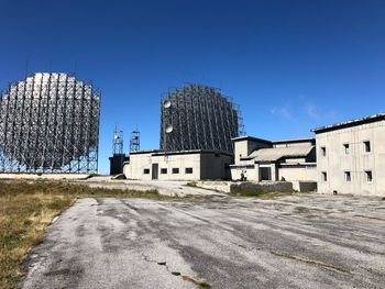 Built structure by buildings against clear blue sky