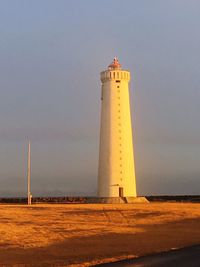 Lighthouse by building against sky