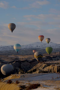 Hot air balloons flying over rock formation against sky in cappadokia