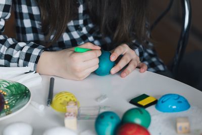 Midsection of girl drawing on easter egg