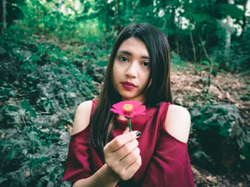 Portrait of beautiful woman holding red flower