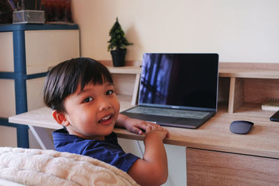 Portrait of boy sitting on table