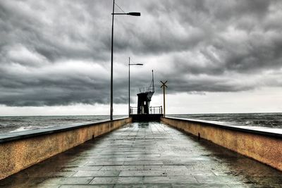 Pier over sea against cloudy sky