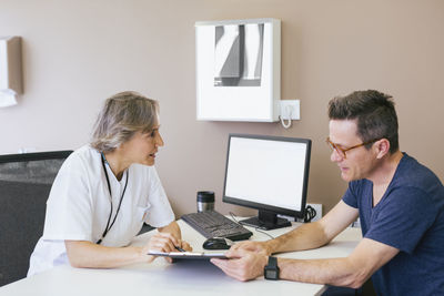 Female doctor discussing with patient while sitting at hospital