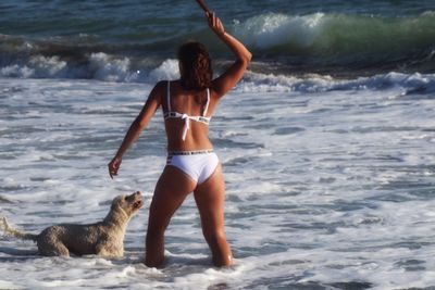 Rear view of woman with dog on beach