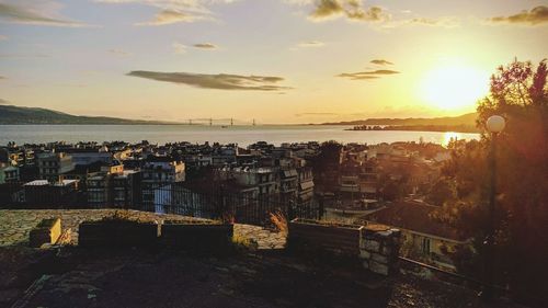 High angle view of townscape by sea against sky during sunset