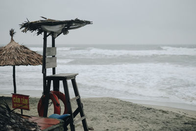 Bird perching on beach against sky