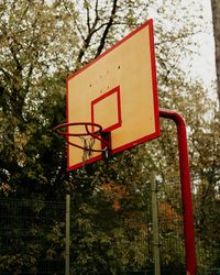 Low angle view of basketball hoop against trees in city