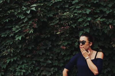 Young woman in sunglasses against plants