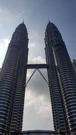 Low angle view of skyscrapers against cloudy sky