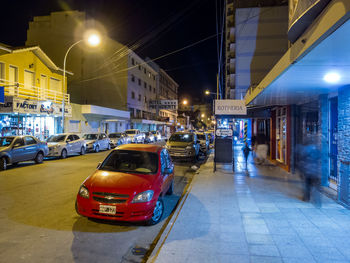 Cars on illuminated city street at night