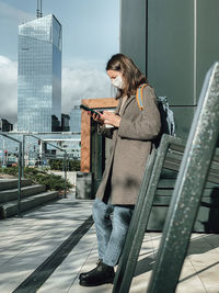 Woman standing by railing in city