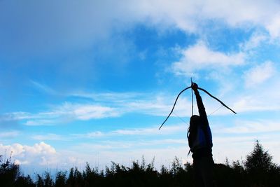 Silhouette of woman standing by tree against sky