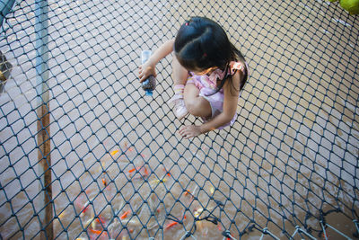 High angle view of woman looking through chainlink fence