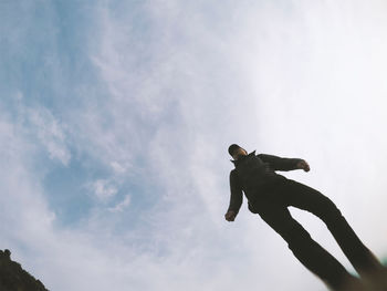 Low angle view of mature man standing against cloudy sky