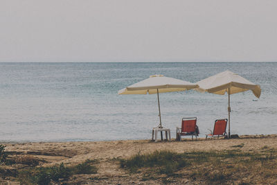 Deck chairs on beach against clear sky