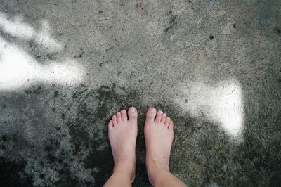 Low section of person standing on wet sand